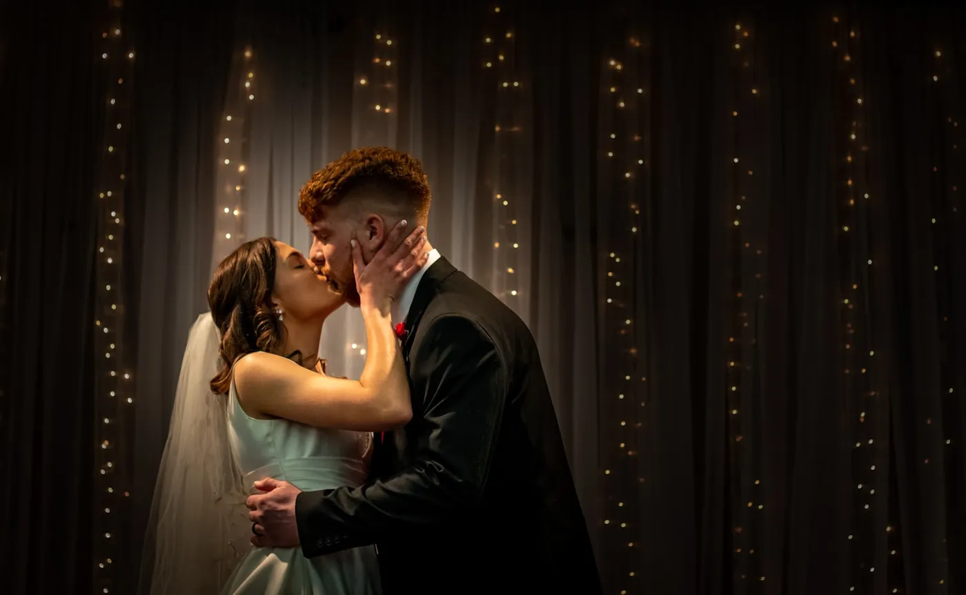 Pareja de novios bailando ante una cortina de luces