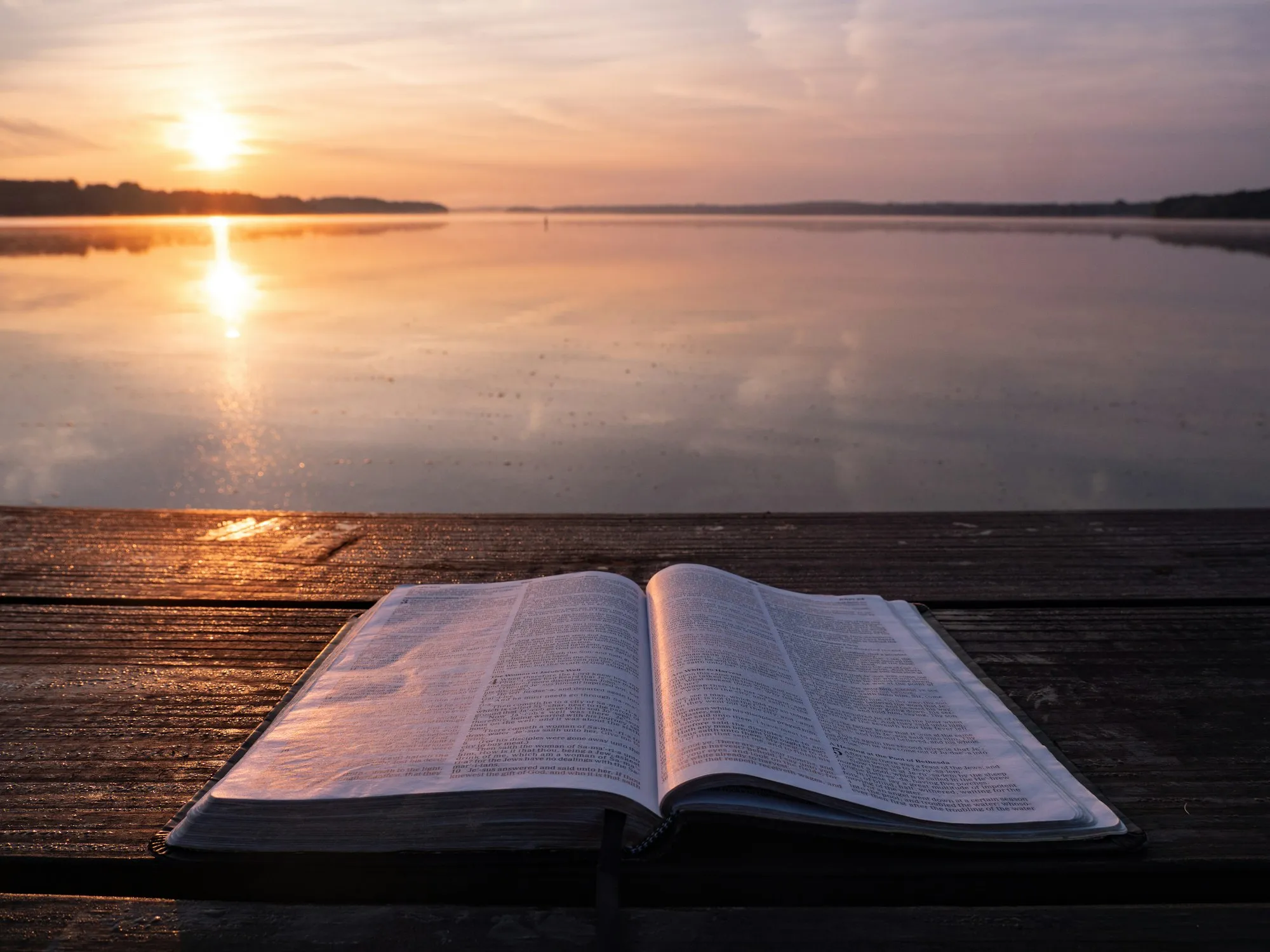 Un libro abierto sobre un muelle de madera al atardecer